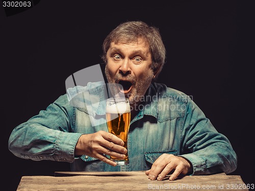 Image of The screaming man in denim shirt with glass of beer