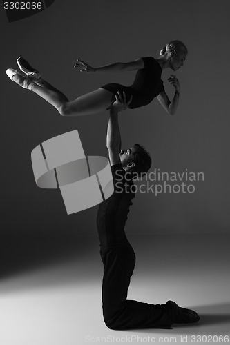 Image of two young modern ballet dancers on gray studio background 