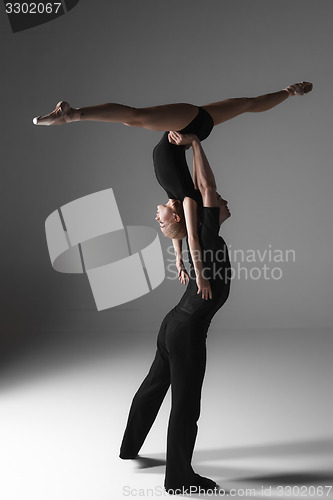 Image of two young modern ballet dancers on gray studio background 