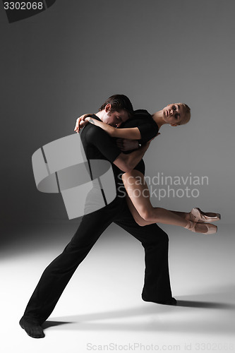 Image of two young modern ballet dancers on gray studio background 