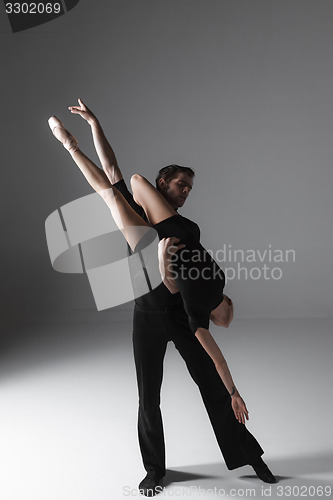 Image of two young modern ballet dancers on gray studio background 