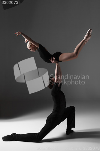 Image of two young modern ballet dancers on gray studio background 