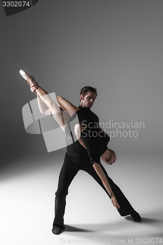 Image of two young modern ballet dancers on gray studio background 