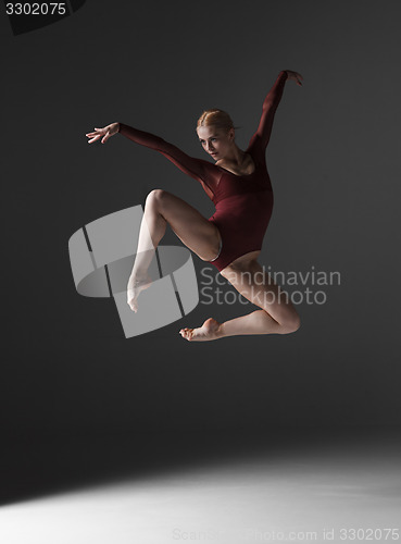 Image of Young beautiful modern style dancer jumping on a studio background