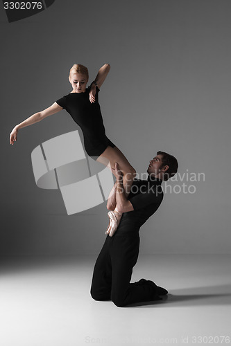 Image of two young modern ballet dancers on gray studio background 