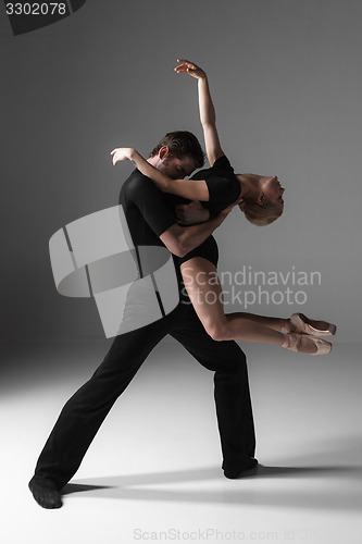 Image of two young modern ballet dancers on gray studio background 