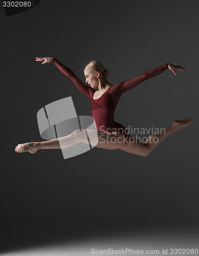 Image of Young beautiful modern style dancer jumping on a studio background