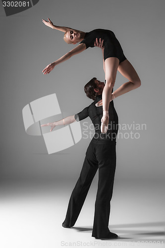 Image of two young modern ballet dancers on gray studio background 