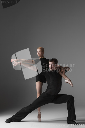 Image of two young modern ballet dancers on gray studio background 