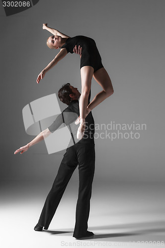 Image of two young modern ballet dancers on gray studio background 