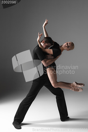 Image of two young modern ballet dancers on gray studio background 