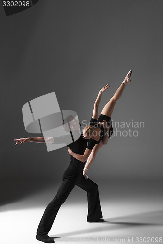 Image of two young modern ballet dancers on gray studio background 