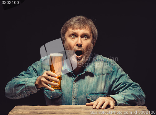 Image of The enchanted and emotional fan with glass of beer