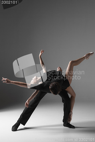 Image of two young modern ballet dancers on gray studio background 