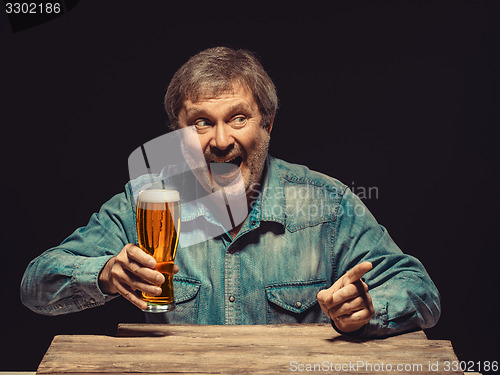 Image of The screaming man in denim shirt with glass of beer