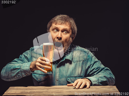 Image of The enchanted and emotional fan with glass of beer