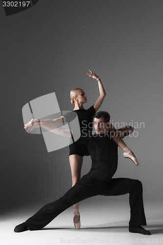 Image of two young modern ballet dancers on gray studio background 