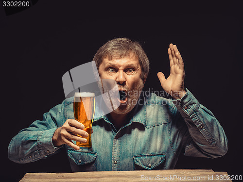 Image of The enchanted and emotional fan with glass of beer