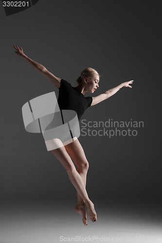 Image of Young beautiful modern style dancer jumping on a studio background