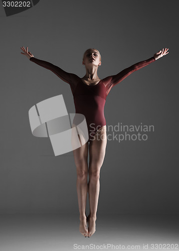Image of Young beautiful modern style dancer jumping on a studio background