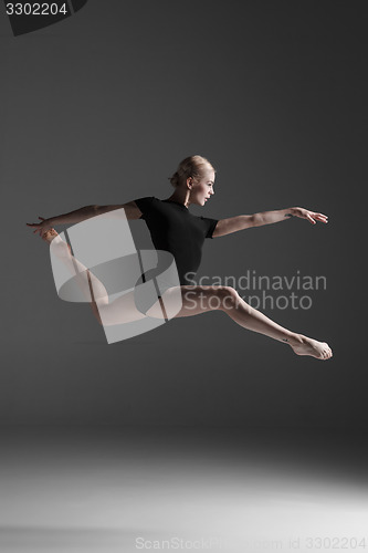 Image of Young beautiful modern style dancer jumping on a studio background