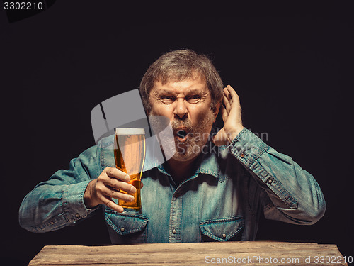 Image of The enchanted and emotional fan with glass of beer