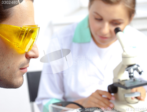 Image of scientist in protective yellow sunglasses and his colleague in l