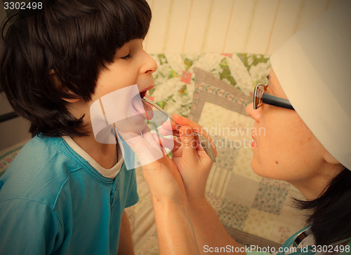 Image of doctor looks throat of boy