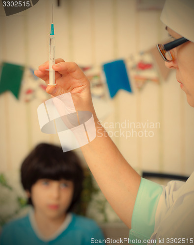 Image of Doctor pediatrician with a syringe and a child in the background