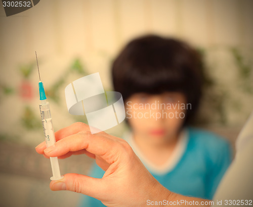 Image of Doctor pediatrician with a syringe and a child in the background