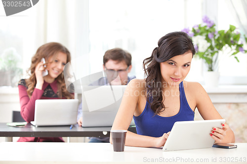 Image of smiling young girl with tablet in cafe