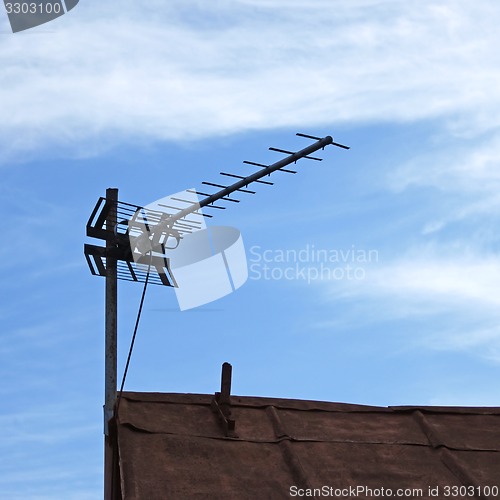 Image of TV antenna over old roof