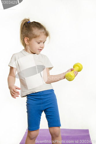 Image of Four-year girl is engaged in raising the dumbbell exercise