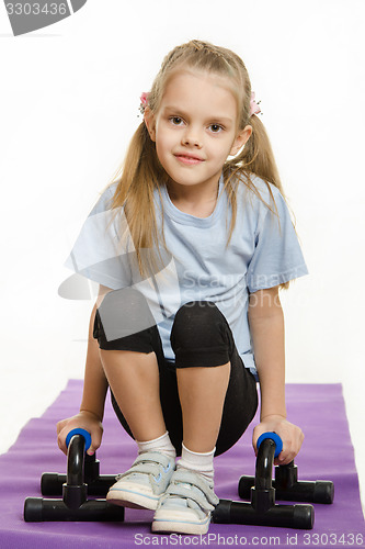 Image of Six year old girl hanging on the palm pushups