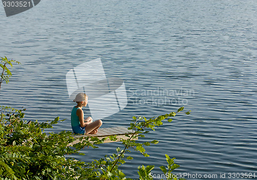 Image of Little girl meditating by the lake