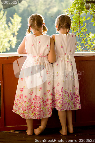 Image of Twin girls on porch in summer dresses