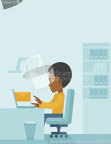 Image of Young african man sitting infront of a computer laptop.