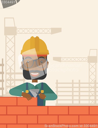 Image of Black builder man is building a brick wall.