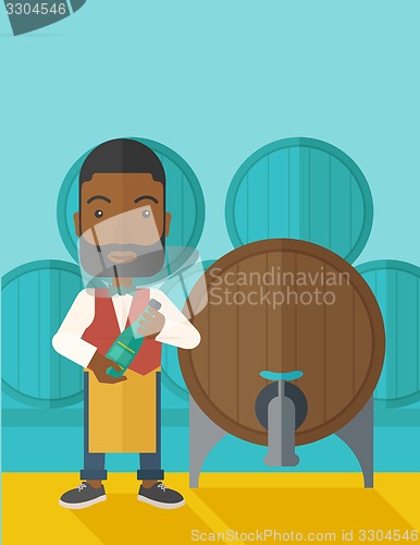 Image of African Wine maker inspecting wine from barrel.