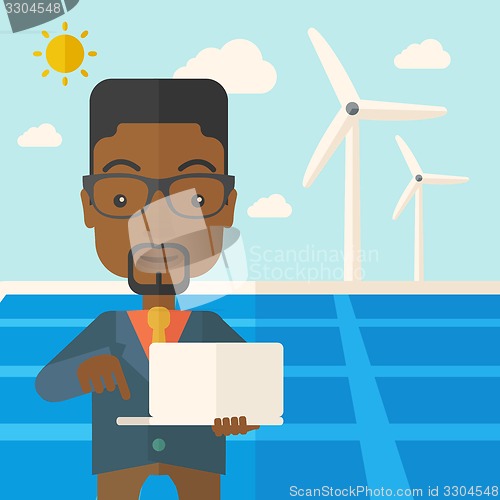 Image of African man with laptop in solar panel.
