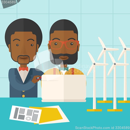 Image of Two black Workers using laptop with windmills.