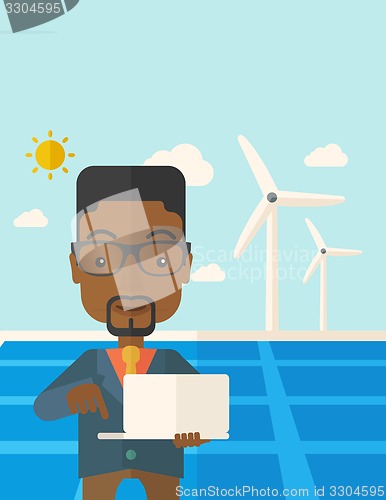 Image of African man with laptop in solar panel.