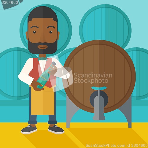 Image of African Wine maker inspecting wine from barrel.