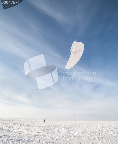 Image of Kiteboarder with blue kite on the snow