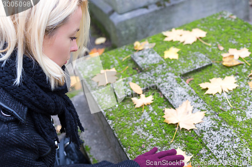 Image of Solitary woman visiting relatives grave.