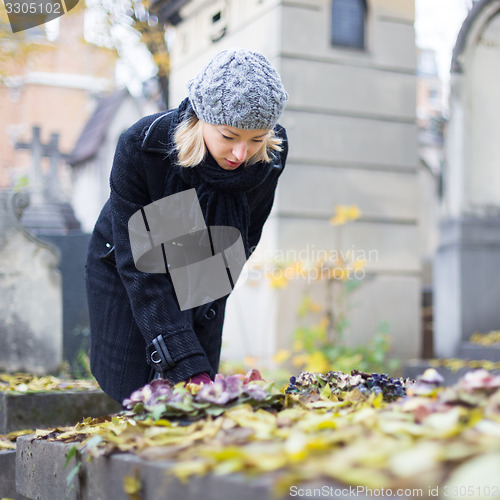 Image of Solitary woman visiting relatives grave.