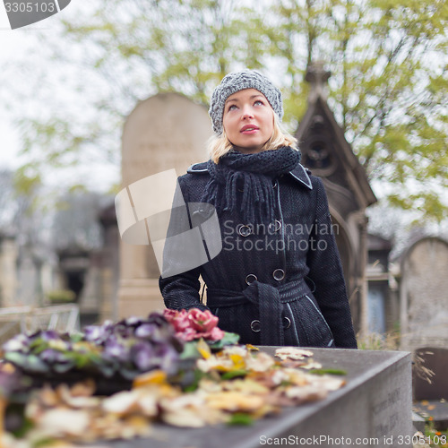 Image of Solitary woman visiting relatives grave.