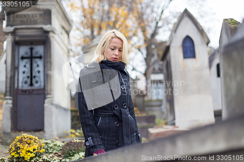 Image of Solitary woman visiting relatives grave.