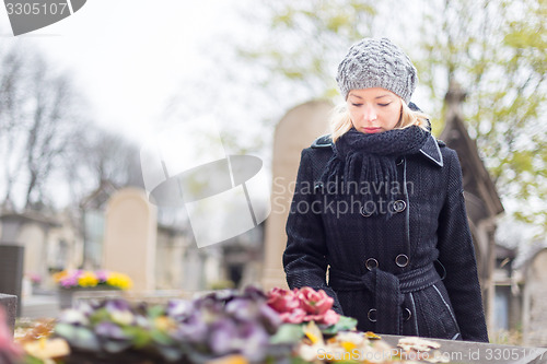 Image of Solitary woman visiting relatives grave.