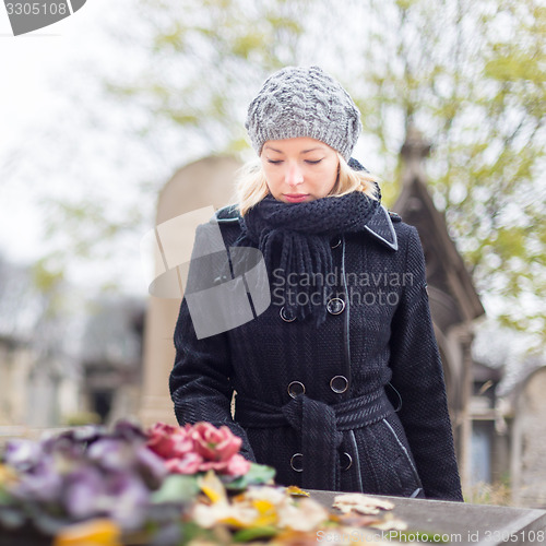 Image of Solitary woman visiting relatives grave.